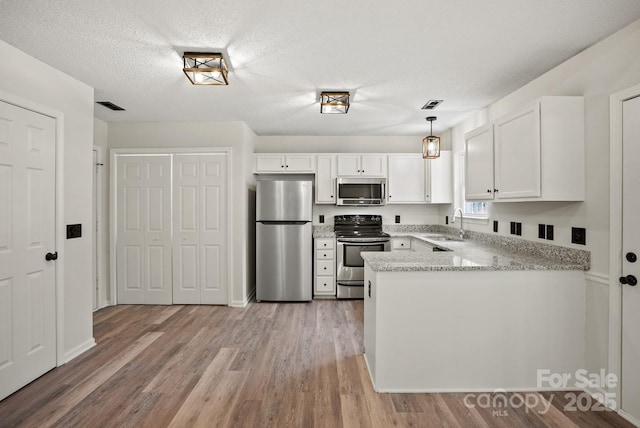 kitchen with a sink, visible vents, appliances with stainless steel finishes, and a peninsula