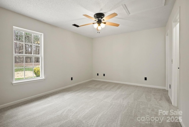 empty room with a textured ceiling, attic access, visible vents, and light carpet