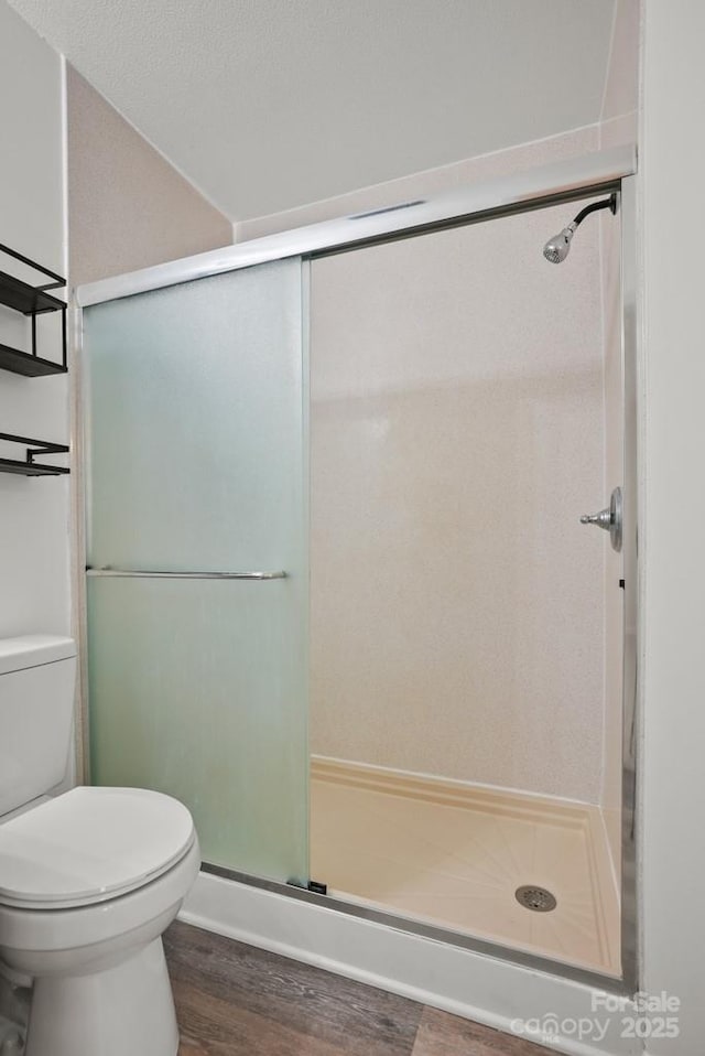 bathroom featuring toilet, wood finished floors, and a shower stall