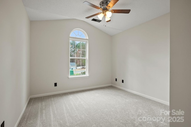 carpeted empty room featuring visible vents, baseboards, a ceiling fan, and vaulted ceiling