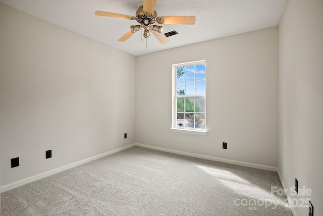 carpeted spare room with a ceiling fan, baseboards, visible vents, and a textured ceiling