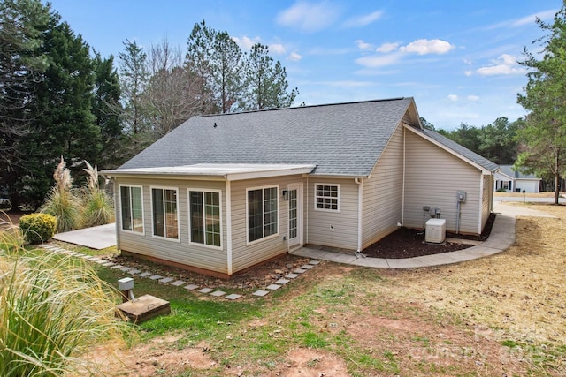 rear view of property with cooling unit and roof with shingles