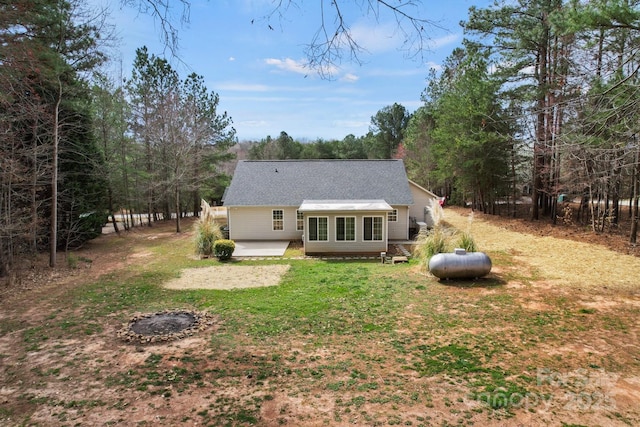 rear view of house with a lawn and roof with shingles