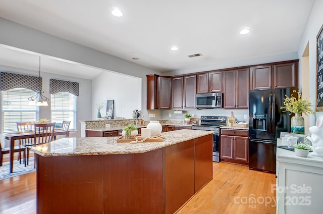 kitchen with visible vents, light stone countertops, light wood-style flooring, and appliances with stainless steel finishes