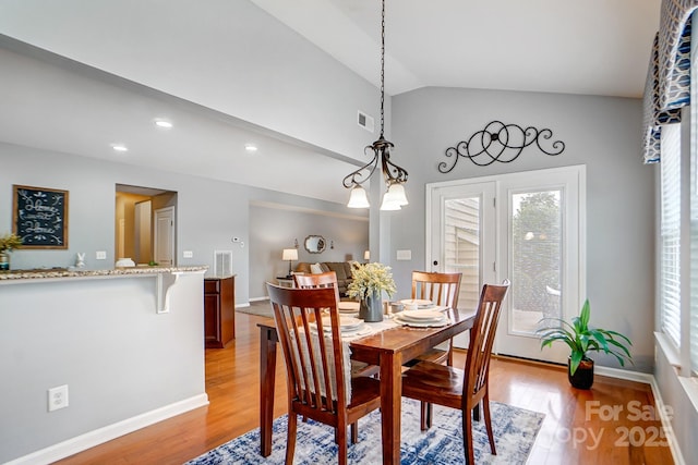 dining room with light wood finished floors, lofted ceiling, visible vents, and a healthy amount of sunlight