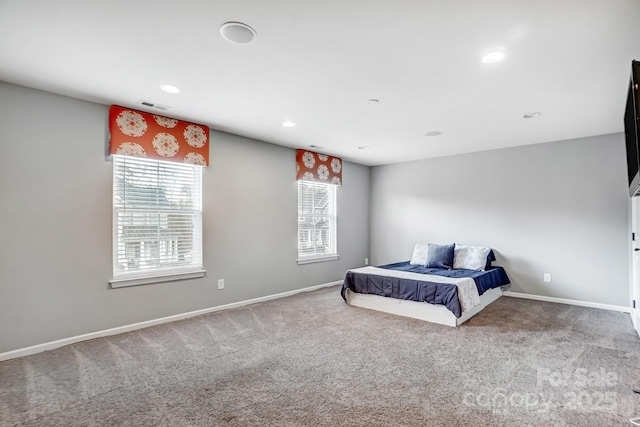 bedroom with carpet floors, visible vents, and multiple windows