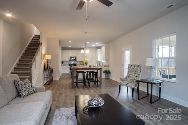 living area with visible vents, wood finished floors, recessed lighting, baseboards, and stairs