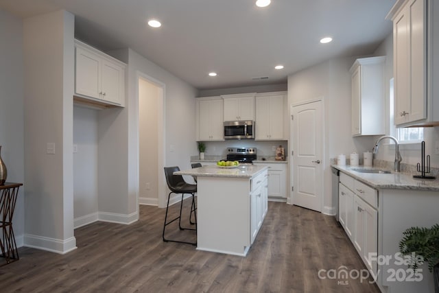 kitchen featuring a kitchen island, white cabinetry, stainless steel appliances, and a sink