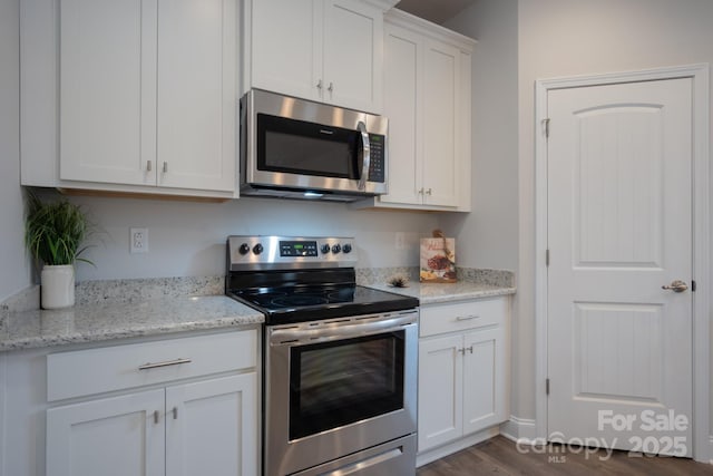 kitchen with white cabinetry, light stone counters, dark wood-style flooring, and stainless steel appliances