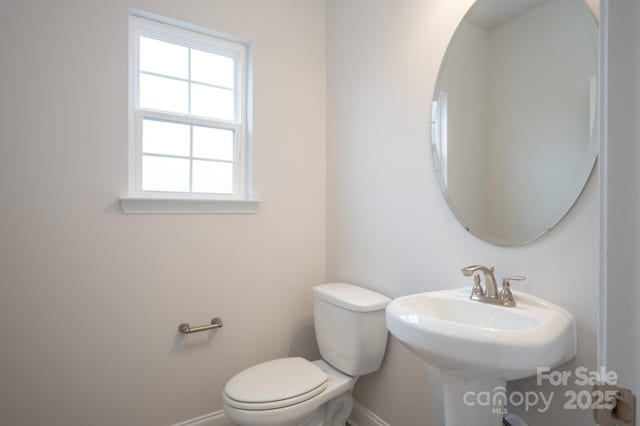 bathroom with a sink, baseboards, and toilet