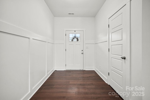 entryway with visible vents, dark wood-type flooring, wainscoting, and a decorative wall