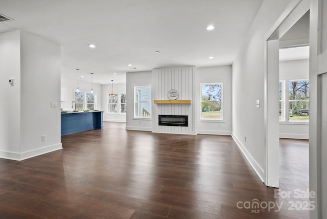 unfurnished living room with recessed lighting, a healthy amount of sunlight, dark wood-style floors, and a sink