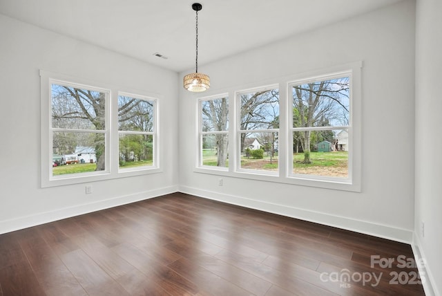 unfurnished dining area with dark wood-style floors, visible vents, and baseboards