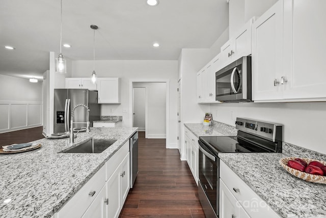 kitchen with a sink, light stone counters, appliances with stainless steel finishes, white cabinetry, and dark wood-style flooring