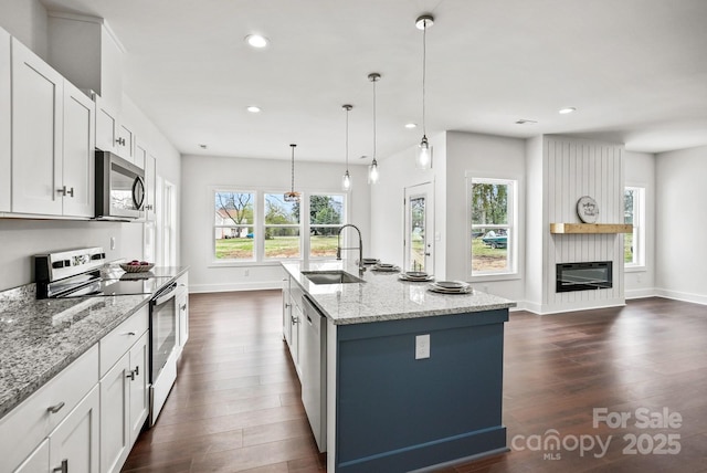 kitchen featuring light stone counters, dark wood-style flooring, appliances with stainless steel finishes, and a sink