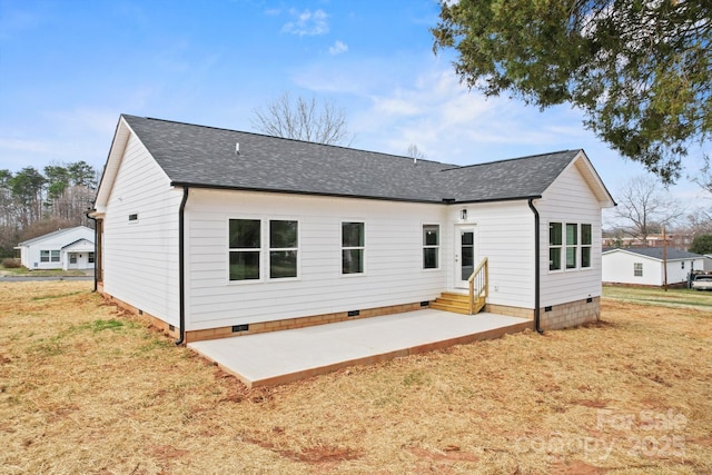 rear view of house with a lawn, entry steps, a patio, a shingled roof, and crawl space