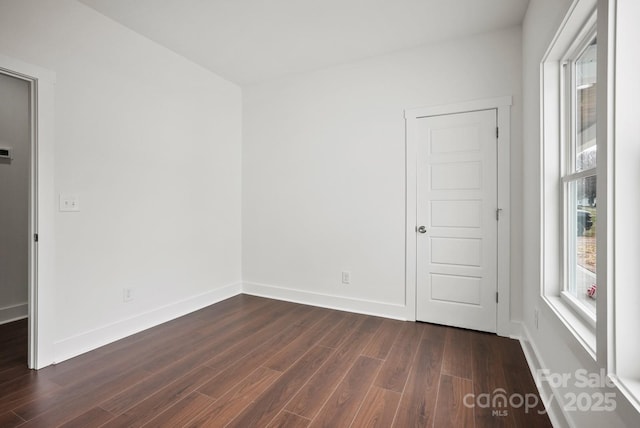 spare room featuring baseboards and dark wood-style flooring