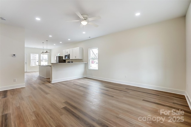 unfurnished living room featuring ceiling fan, baseboards, wood finished floors, and recessed lighting