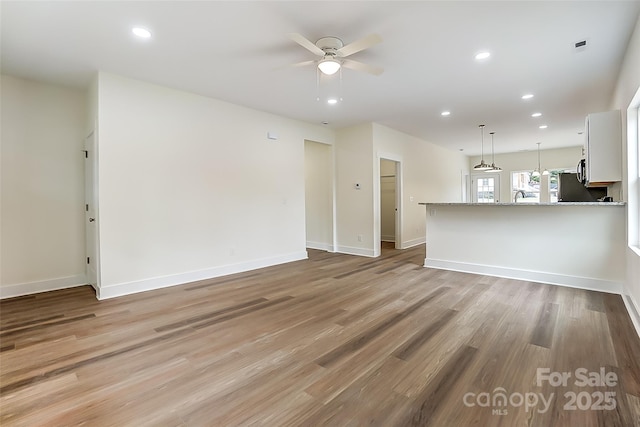 unfurnished living room featuring light wood finished floors, recessed lighting, baseboards, and a ceiling fan