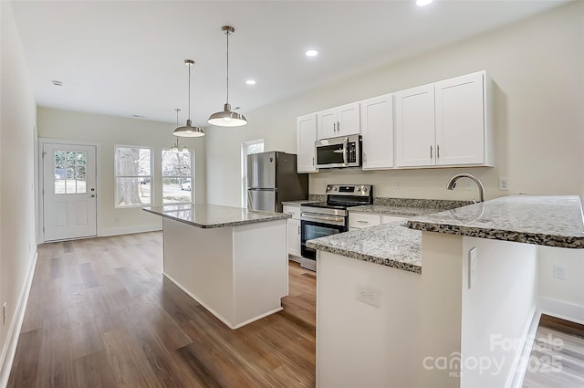 kitchen with light stone counters, appliances with stainless steel finishes, white cabinets, and light wood finished floors