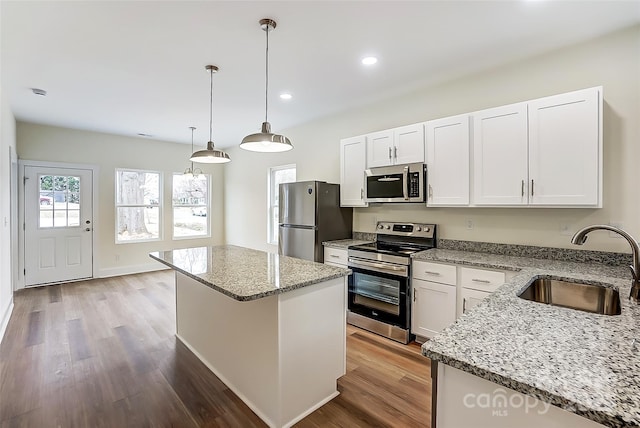 kitchen with a sink, stainless steel appliances, wood finished floors, and white cabinets