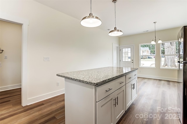 kitchen featuring light stone counters, decorative light fixtures, baseboards, and dark wood-style flooring