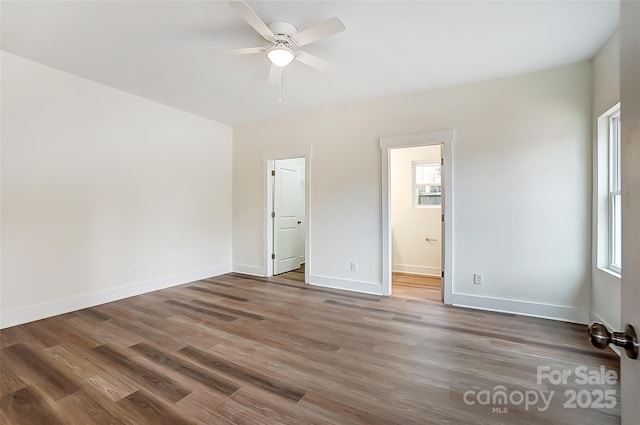 unfurnished bedroom featuring multiple windows, wood finished floors, and baseboards