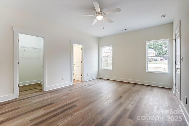 unfurnished bedroom featuring multiple windows, light wood-style floors, and baseboards