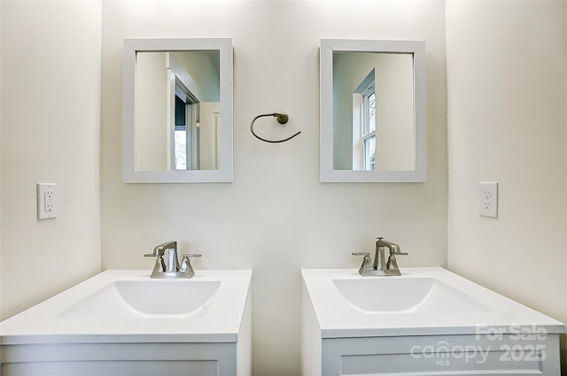 bathroom featuring plenty of natural light, two vanities, and a sink