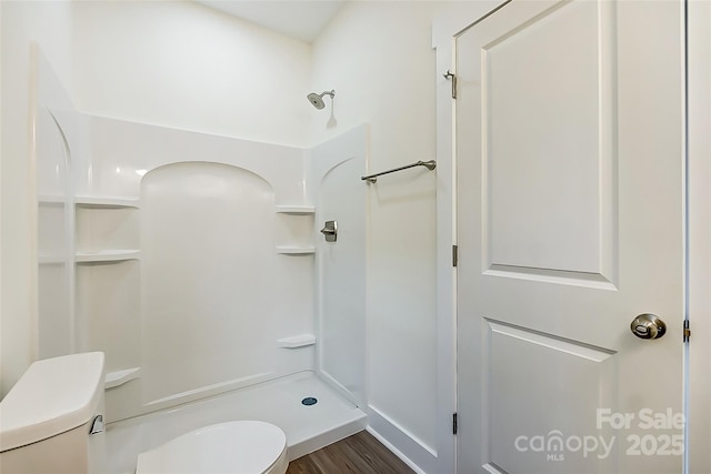 bathroom featuring wood finished floors, toilet, and a shower