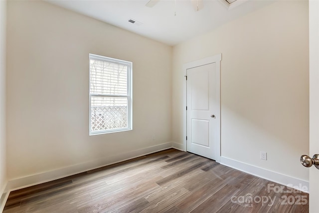 empty room featuring visible vents, a ceiling fan, baseboards, and wood finished floors