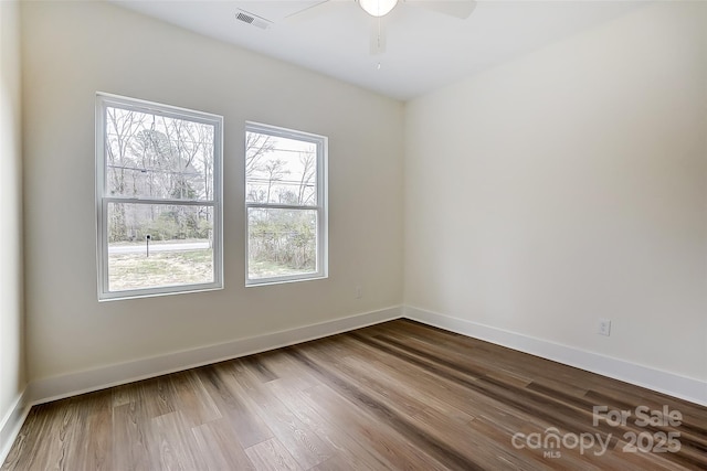 unfurnished room with visible vents, a ceiling fan, dark wood-type flooring, and baseboards