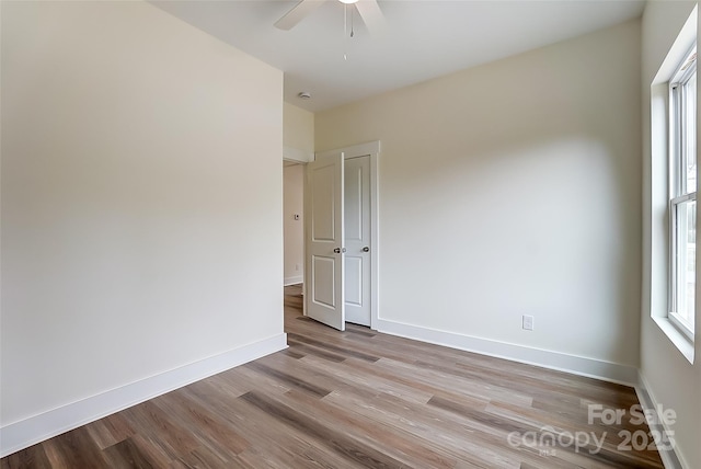 empty room with ceiling fan, baseboards, and wood finished floors