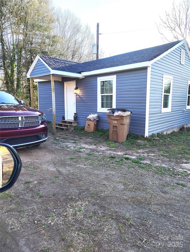 back of house with roof with shingles and entry steps