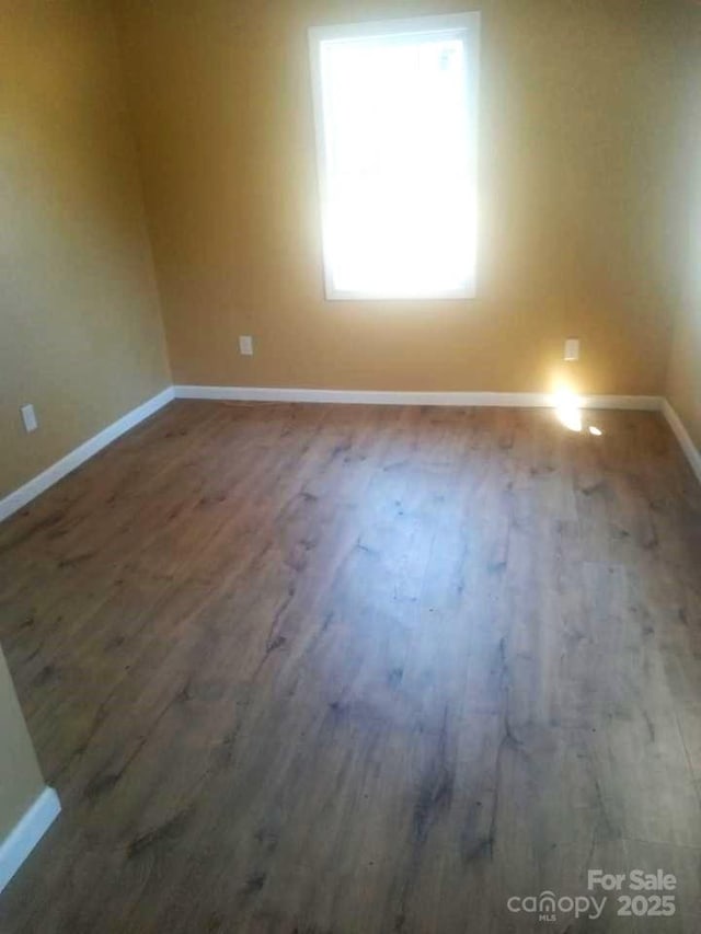 spare room featuring wood finished floors and baseboards