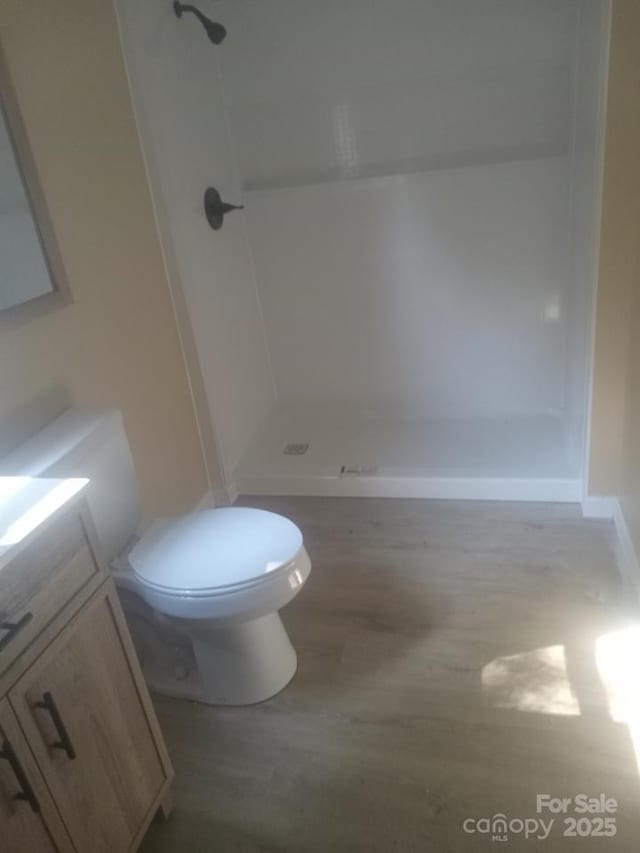 full bathroom featuring wood finished floors, toilet, a stall shower, and vanity