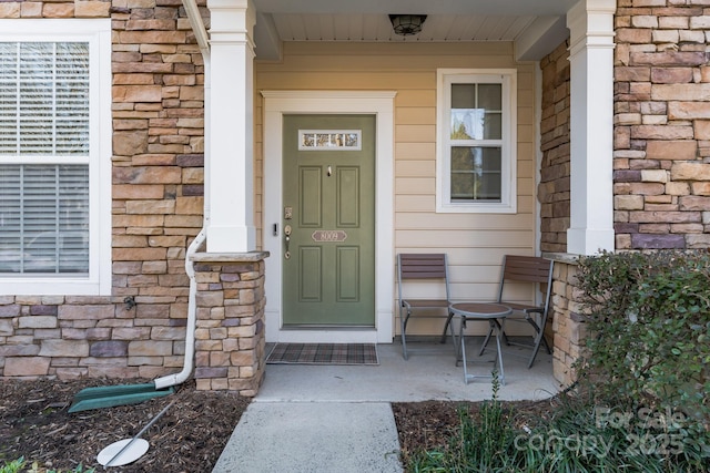 entrance to property with covered porch and stone siding