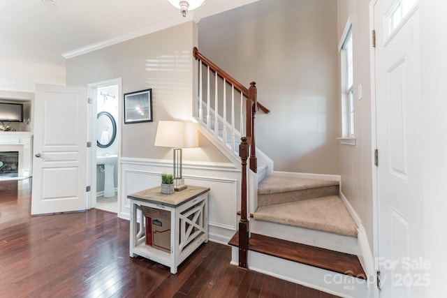 stairway with a glass covered fireplace, baseboards, wood-type flooring, and ornamental molding