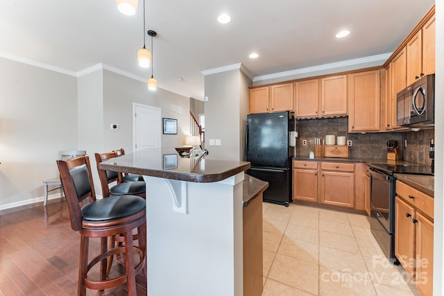 kitchen with a kitchen bar, tasteful backsplash, dark countertops, and black appliances