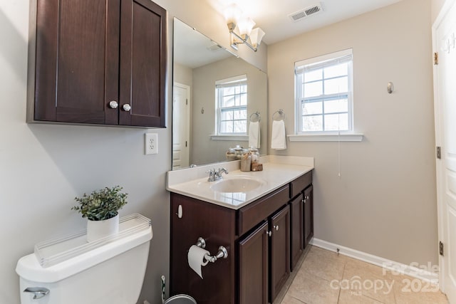 half bath with visible vents, toilet, tile patterned flooring, baseboards, and vanity