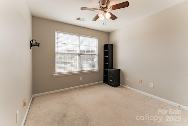 carpeted spare room with visible vents, baseboards, and ceiling fan