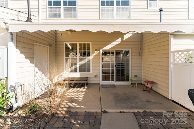 property entrance featuring fence and a patio area