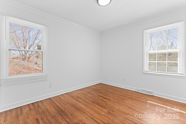 unfurnished room featuring baseboards, visible vents, crown molding, and wood finished floors