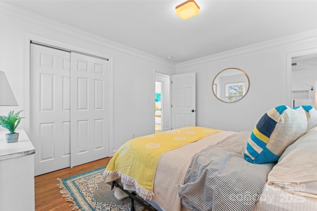 bedroom with a closet, crown molding, and light wood finished floors