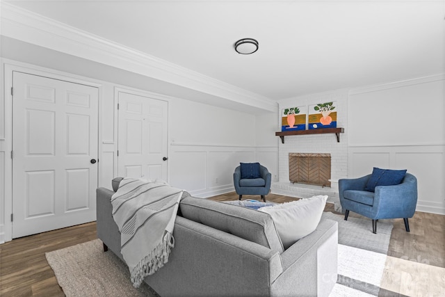 living room with a decorative wall, crown molding, and wood finished floors