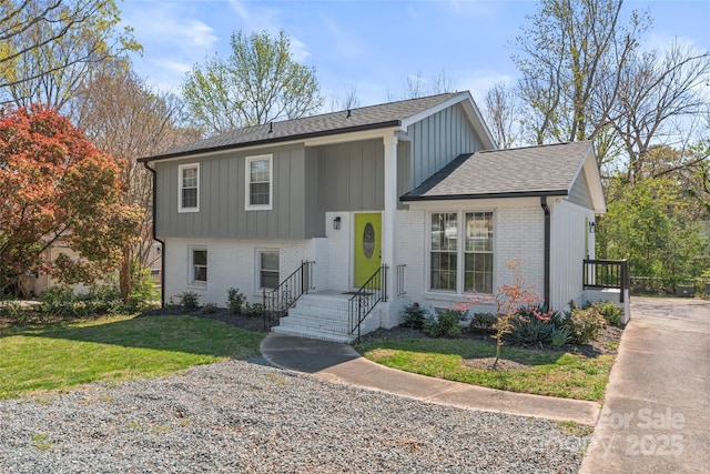 view of front of house featuring brick siding, a front lawn, and board and batten siding
