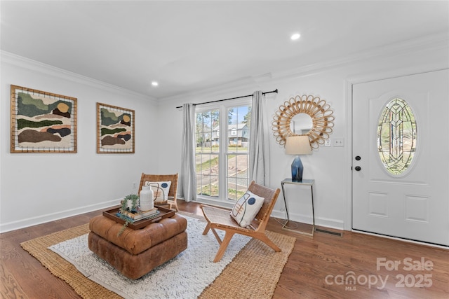 sitting room with baseboards, wood finished floors, recessed lighting, and crown molding