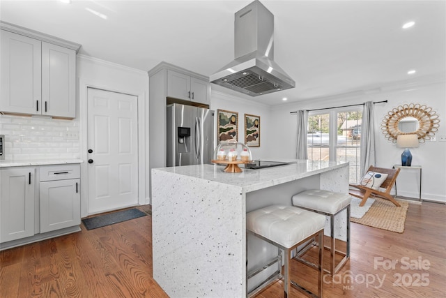 kitchen with backsplash, stainless steel fridge, dark wood finished floors, island range hood, and ornamental molding