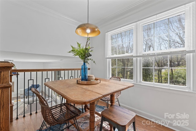 dining room featuring baseboards, ornamental molding, and light wood-style flooring