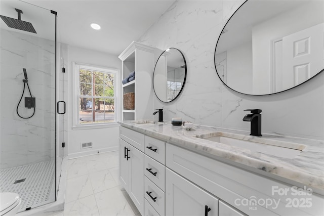 bathroom with a marble finish shower, marble finish floor, visible vents, and a sink